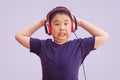 Asian boy wearing headphones listening to music and crazy and screaming excited, isolated on grey background Royalty Free Stock Photo