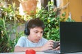 Asian boy wearing headphones and white shirt smiling and playing a game on smart phone Royalty Free Stock Photo