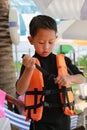 Asian boy wearing life jacket before playing in pool. Kid with life vests. Water safety for children Royalty Free Stock Photo