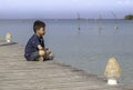 Asian boy on the wooden bridge pier boat in the sea and the bright sky at Koh Kood, Trat in Thailand Royalty Free Stock Photo