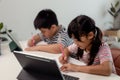 Asian boys and girls enjoy online learning by taking notes and using tablets at home