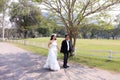 Asian bride and her groom walking down the garden in the sunshine Royalty Free Stock Photo