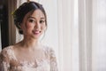 Asian bride standing near window in dressing room Royalty Free Stock Photo