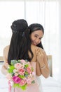 An Asian bride in a white wedding dress embraces her friend in a pink dress with a smile, then shows a diamond ring on her left Royalty Free Stock Photo