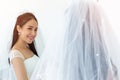 An Asian bride in a white wedding dress stands smiling brightly in front of a mirror reflection Royalty Free Stock Photo