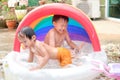 Asian brother and sister having fun playing with water, splashing in inflatable pool at home Royalty Free Stock Photo