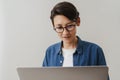 Asian brunette boy wearing eyeglasses working with laptop Royalty Free Stock Photo