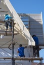 Asian builder workers with work tools on scaffolding are working to renovate external roof structure of the old house building in