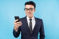 Asian buisnessman wearing suit holding smartphone on blue background