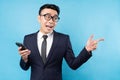 Asian buisnessman wearing suit holding smartphone on blue background