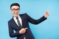 Asian buisnessman wearing suit pointing on blue background