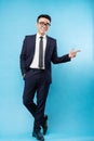 Asian buisnessman wearing suit standing and pointing on blue background