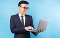 Asian buisnessman wearing suit and using laptop on blue background