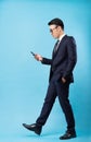 Asian buisnessman wearing suit and walking on blue background