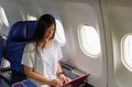 Asian businees woman comercial plane passenger using laptop on board for working while sitting in airplane. Traveling and Royalty Free Stock Photo