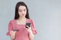 Asian business female who wears pink dress holds smartphone and credit card in her hands in finance choice theme Royalty Free Stock Photo