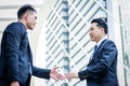 Two asian business have handshake with building and city background.