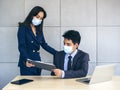 Asian business man and woman wearing suit and protective face masks using computer on desk, meeting and working together in office Royalty Free Stock Photo