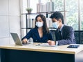 Asian business man and woman wearing suit and protective face masks using computer on desk, meeting and working together in office Royalty Free Stock Photo