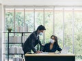 Asian business man and woman wearing suit and protective face masks using computer on desk, meeting and working together in office Royalty Free Stock Photo