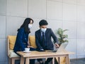 Asian business man and woman wearing suit and protective face masks using computer on desk, meeting and working together in office Royalty Free Stock Photo