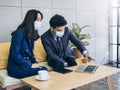 Asian business man and woman wearing suit and protective face masks using computer on desk, meeting and working together in office Royalty Free Stock Photo