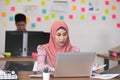 Asian business Muslim or islam women in casual working with laptop and smile looking at camera at modern office