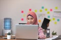Asian business Muslim or islam women in casual working with laptop and smile looking at camera at modern office