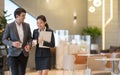 Asian business people  walking in office building. Young businessman and businesswoman talking when walking. Royalty Free Stock Photo