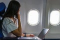 Asian business woman commercial plane passenger using laptop on board for working while sitting in airplane. Traveling and Royalty Free Stock Photo