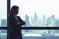 Asian business woman crossed arms looking out the window at city view background Royalty Free Stock Photo