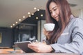 Asian business woman holding and looking at tablet pc while drinking coffee in modern cafe Royalty Free Stock Photo