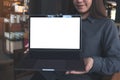 An Asian business woman holding , presenting and showing laptop with blank white screen in modern cafe Royalty Free Stock Photo