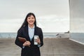 Asian business woman holding smart tablet and drinking take away coffee outside office Royalty Free Stock Photo