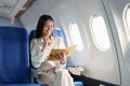 Asian business woman passenger sitting on business class luxury plane while working using notebook book while travel Royalty Free Stock Photo