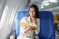 Asian business woman passenger sitting on business class luxury plane while working using notebook book while travel Royalty Free Stock Photo