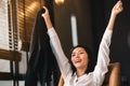 An Asian business woman is raising hands and smiling, happy with the work done