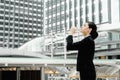 Asian business woman standing and drinking pure mineral water from plastic bottle with background of building. Royalty Free Stock Photo