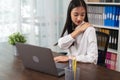 Asian business woman suffers from shoulder pain from working with computers for a long time.