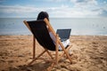 Asian business woman with tablet computer during tropical beach vacation. Freelancer working on laptop lying on sun lounger. Royalty Free Stock Photo