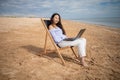 Asian business woman with tablet computer during tropical beach vacation. Freelancer working on laptop lying on sun lounger. Royalty Free Stock Photo