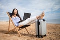 Asian business woman with tablet computer during tropical beach vacation. Freelancer working on laptop lying on sun lounger. Royalty Free Stock Photo