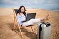 Asian business woman with tablet computer during tropical beach vacation. Freelancer working on laptop lying on sun lounger. Royalty Free Stock Photo