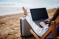 Asian business woman with tablet computer during tropical beach vacation. Freelancer working on laptop lying on sun lounger.