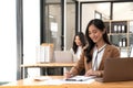 Asian Business woman using calculator and laptop for doing math finance on an office desk, tax, report, accounting Royalty Free Stock Photo