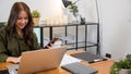 Asian business woman using laptop checking smartphone indoors home office Royalty Free Stock Photo