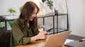 Asian business woman using laptop checking smartphone indoors home office Royalty Free Stock Photo