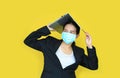 Asian business woman wearing medical shielding mask with laptop computer on her head isolated on yellow background Royalty Free Stock Photo