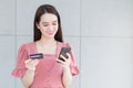 Asian business woman who wears pink dress holds smartphone and credit card in her hands in finance choice theme Royalty Free Stock Photo