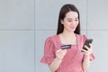 Asian business woman who wears pink dress holds smartphone and credit card in her hands in finance choice theme Royalty Free Stock Photo